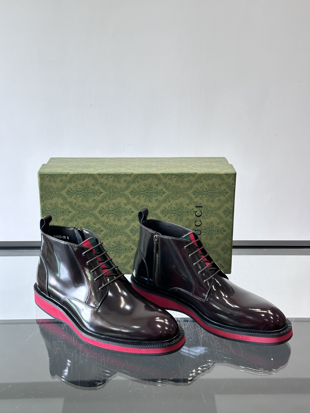 Gucci经典的拼色切尔西靴，采用高光泽黑色皮革搭配标志性的红绿织带细节，鞋底为亮眼的红色，整体设计兼具