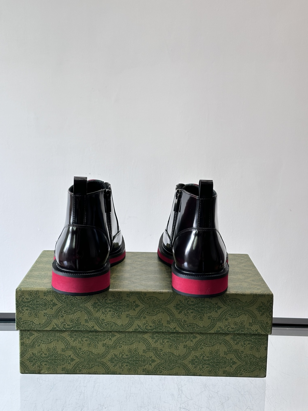 Gucci经典的拼色切尔西靴，采用高光泽黑色皮革搭配标志性的红绿织带细节，鞋底为亮眼的红色，整体设计兼具