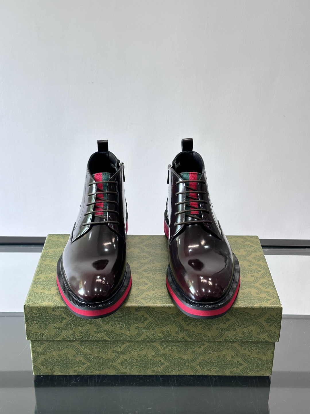 Gucci经典的拼色切尔西靴，采用高光泽黑色皮革搭配标志性的红绿织带细节，鞋底为亮眼的红色，整体设计兼具