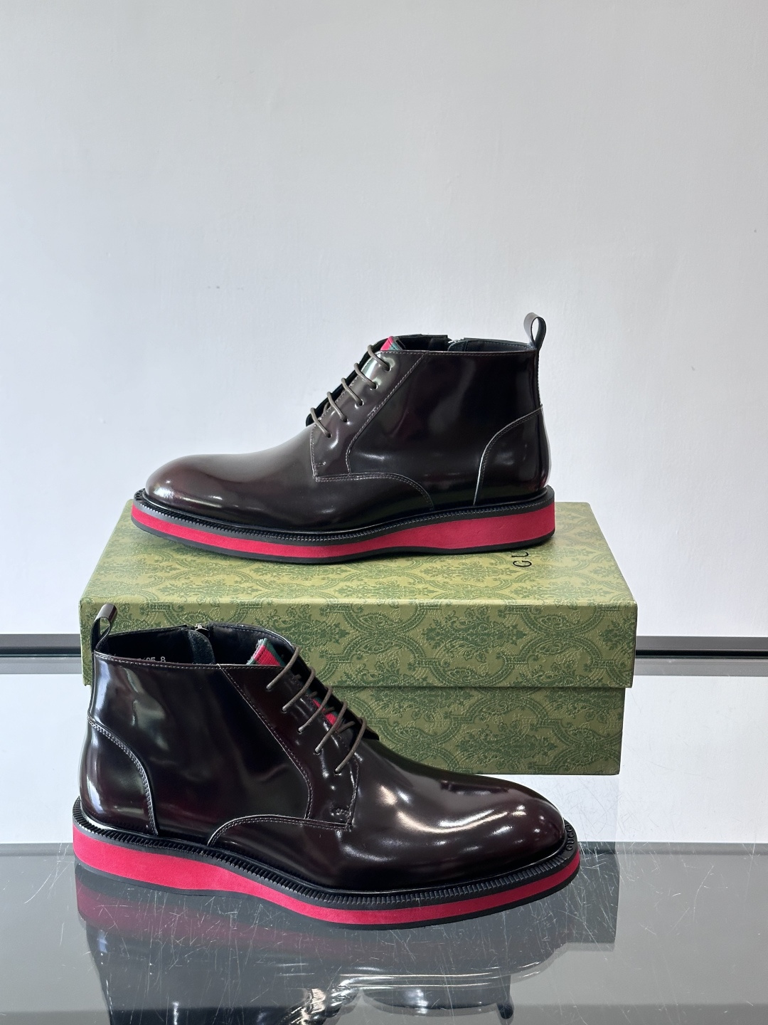 Gucci经典的拼色切尔西靴，采用高光泽黑色皮革搭配标志性的红绿织带细节，鞋底为亮眼的红色，整体设计兼具
