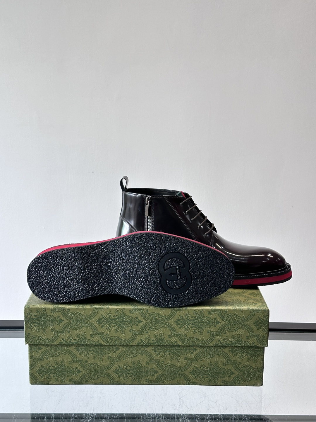 Gucci经典的拼色切尔西靴，采用高光泽黑色皮革搭配标志性的红绿织带细节，鞋底为亮眼的红色，整体设计兼具