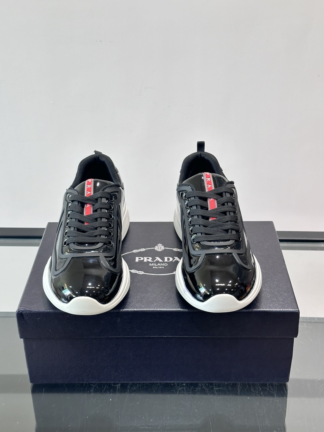 Prada经典漆皮厚底运动鞋，鞋面采用高光泽感的漆皮材质，搭配厚底和黑色鞋带，整体设计复古又时髦，带有强