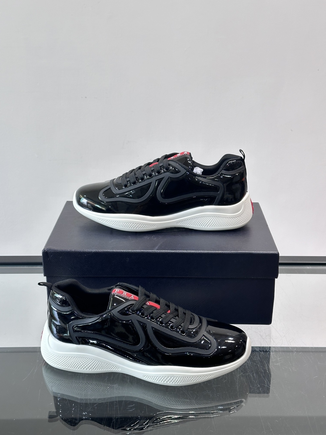 Prada经典漆皮厚底运动鞋，鞋面采用高光泽感的漆皮材质，搭配厚底和黑色鞋带，整体设计复古又时髦，带有强