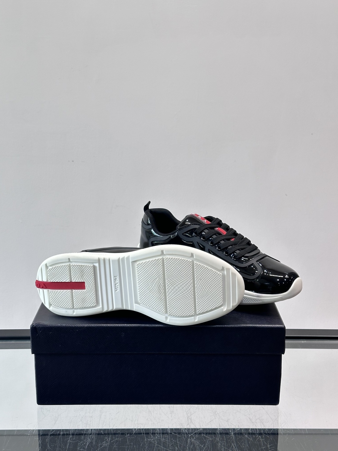 Prada经典漆皮厚底运动鞋，鞋面采用高光泽感的漆皮材质，搭配厚底和黑色鞋带，整体设计复古又时髦，带有强