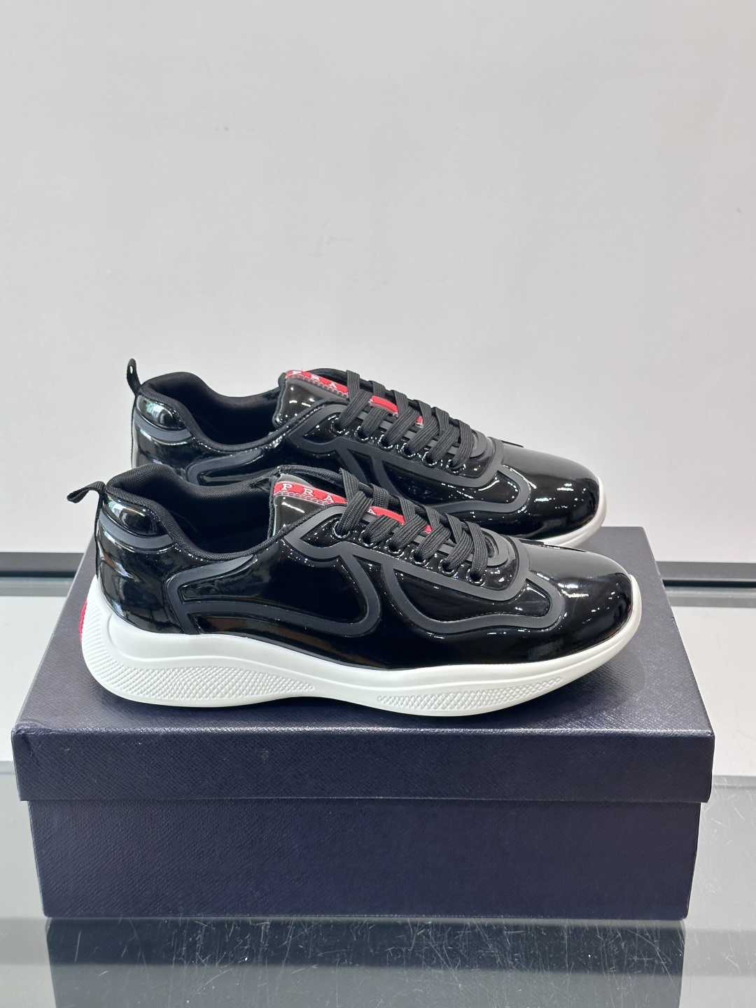 Prada经典漆皮厚底运动鞋，鞋面采用高光泽感的漆皮材质，搭配厚底和黑色鞋带，整体设计复古又时髦，带有强