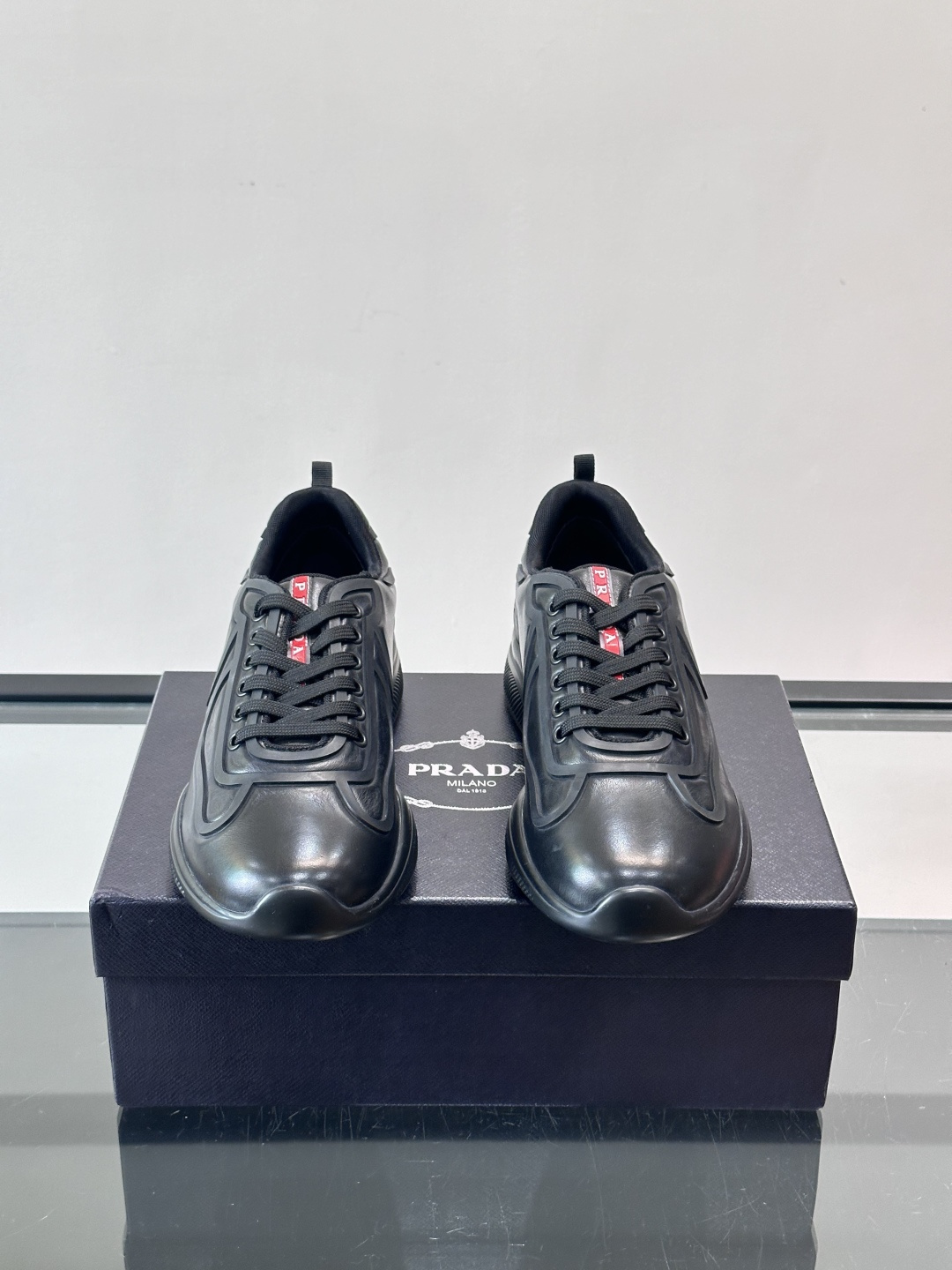 Prada经典漆皮厚底运动鞋，鞋面采用高光泽感的漆皮材质，搭配厚底和黑色鞋带，整体设计复古又时髦，带有强