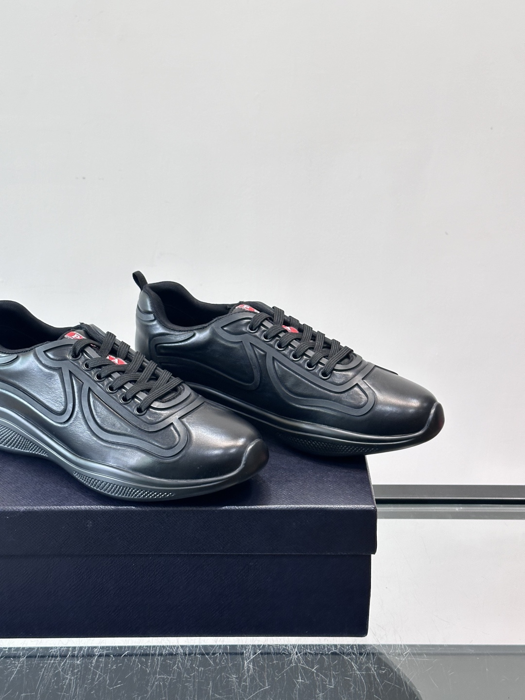 Prada经典漆皮厚底运动鞋，鞋面采用高光泽感的漆皮材质，搭配厚底和黑色鞋带，整体设计复古又时髦，带有强