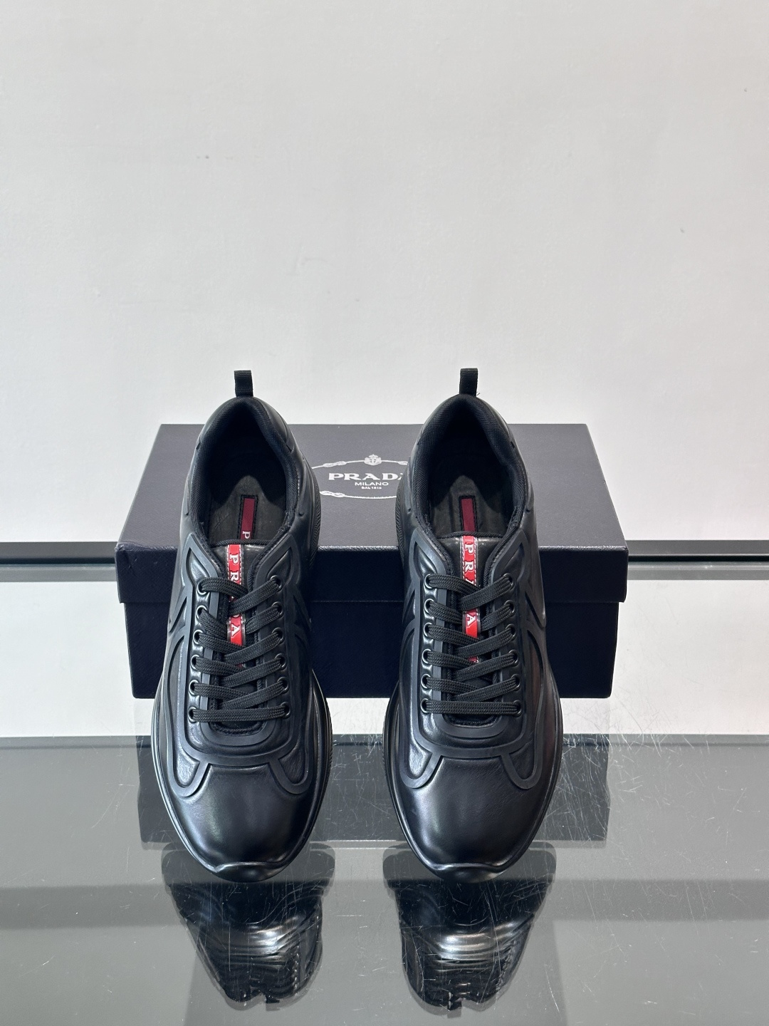 Prada经典漆皮厚底运动鞋，鞋面采用高光泽感的漆皮材质，搭配厚底和黑色鞋带，整体设计复古又时髦，带有强