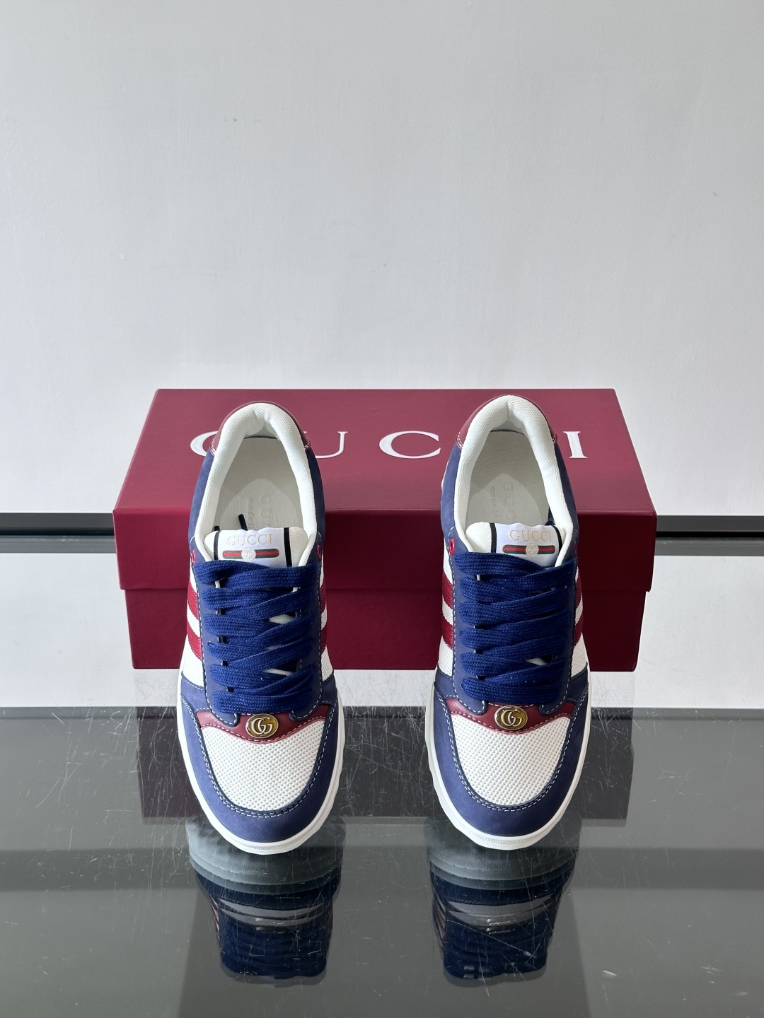 这双也是 ​​Gucci RE-WEB 运动鞋​​，白色皮革鞋身搭配红色织带条纹，金色 GG 金属扣，鞋