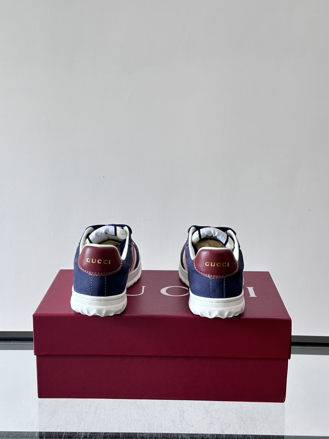 这双也是 ​​Gucci RE-WEB 运动鞋​​，白色皮革鞋身搭配红色织带条纹，金色 GG 金属扣，鞋