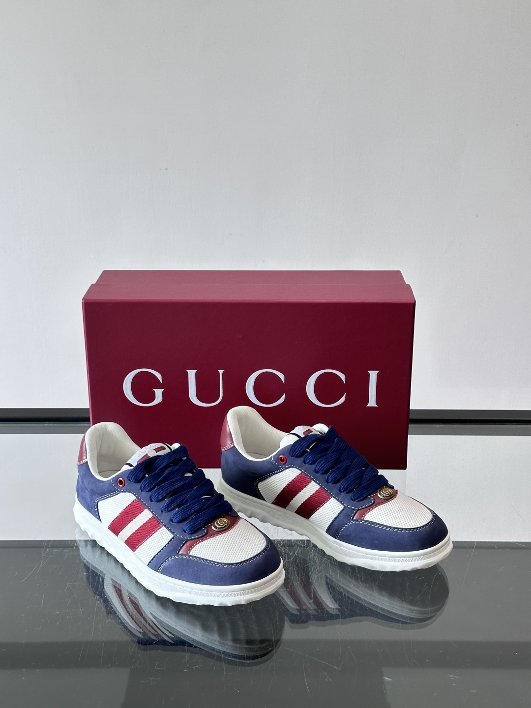 这双也是 ​​Gucci RE-WEB 运动鞋​​，白色皮革鞋身搭配红色织带条纹，金色 GG 金属扣，鞋