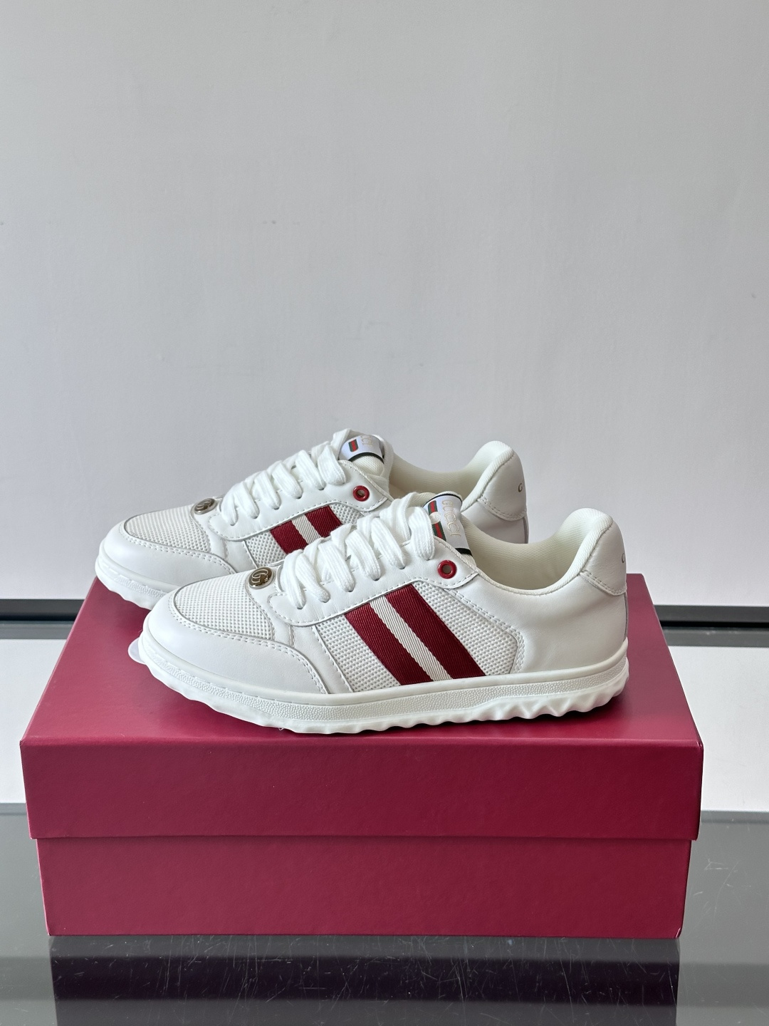 这双也是 ​​Gucci RE-WEB 运动鞋​​，白色皮革鞋身搭配红色织带条纹，金色 GG 金属扣，鞋
