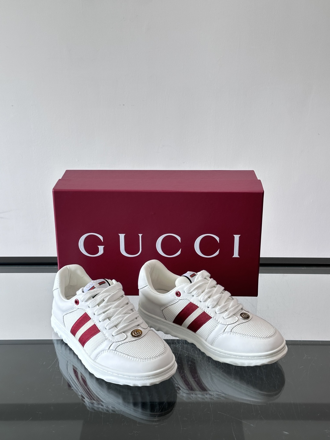 这双也是 ​​Gucci RE-WEB 运动鞋​​，白色皮革鞋身搭配红色织带条纹，金色 GG 金属扣，鞋