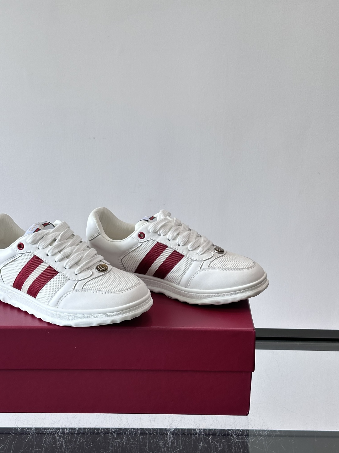 这双也是 ​​Gucci RE-WEB 运动鞋​​，白色皮革鞋身搭配红色织带条纹，金色 GG 金属扣，鞋