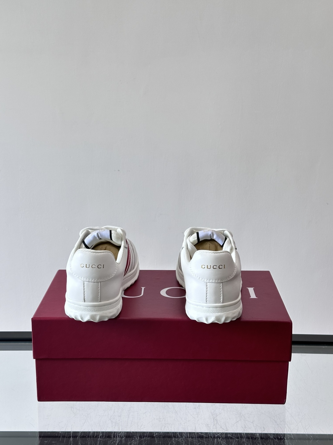 这双也是 ​​Gucci RE-WEB 运动鞋​​，白色皮革鞋身搭配红色织带条纹，金色 GG 金属扣，鞋