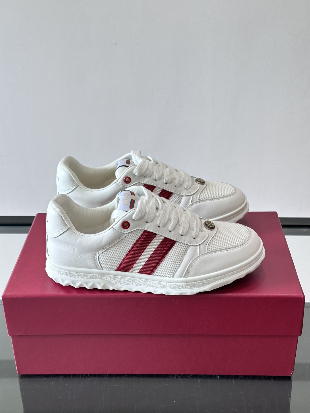 这双也是 ​​Gucci RE-WEB 运动鞋​​，白色皮革鞋身搭配红色织带条纹，金色 GG 金属扣，鞋