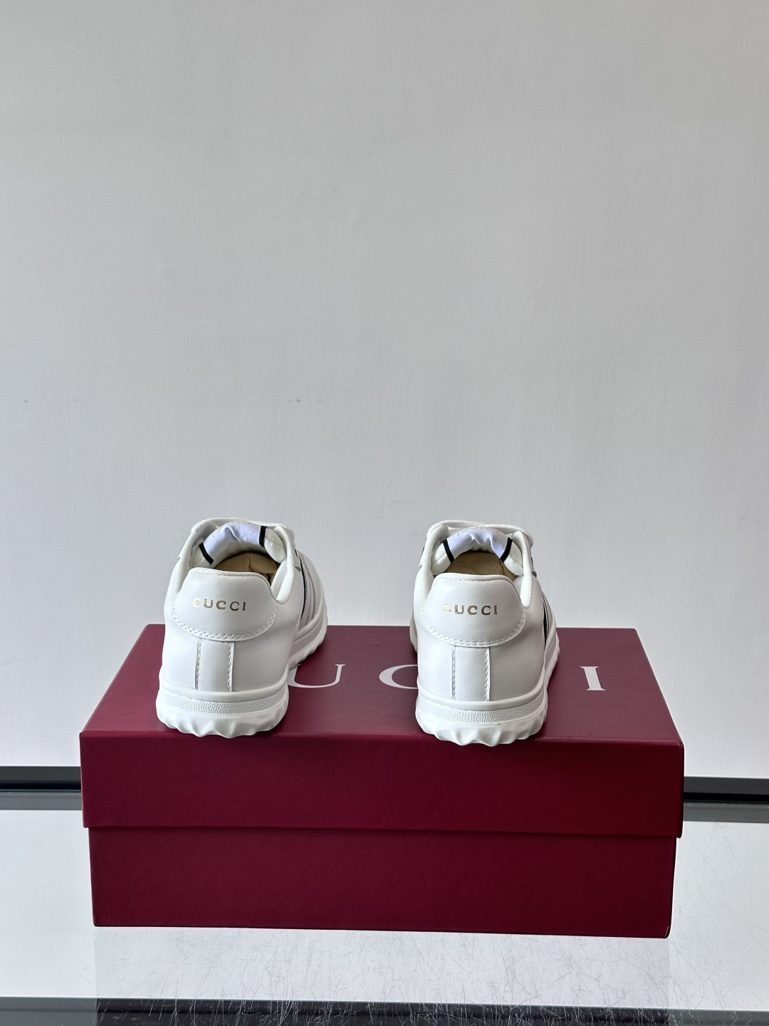 这双也是 ​​Gucci RE-WEB 运动鞋​​，白色皮革鞋身搭配红色织带条纹，金色 GG 金属扣，鞋