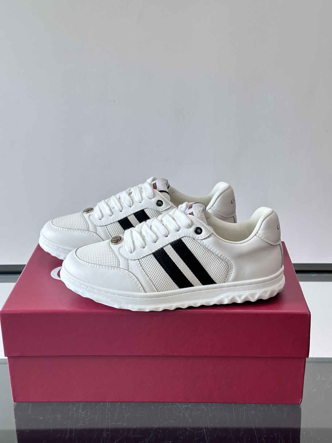 这双也是 ​​Gucci RE-WEB 运动鞋​​，白色皮革鞋身搭配红色织带条纹，金色 GG 金属扣，鞋