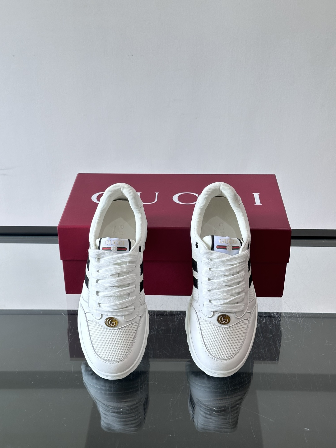 这双也是 ​​Gucci RE-WEB 运动鞋​​，白色皮革鞋身搭配红色织带条纹，金色 GG 金属扣，鞋