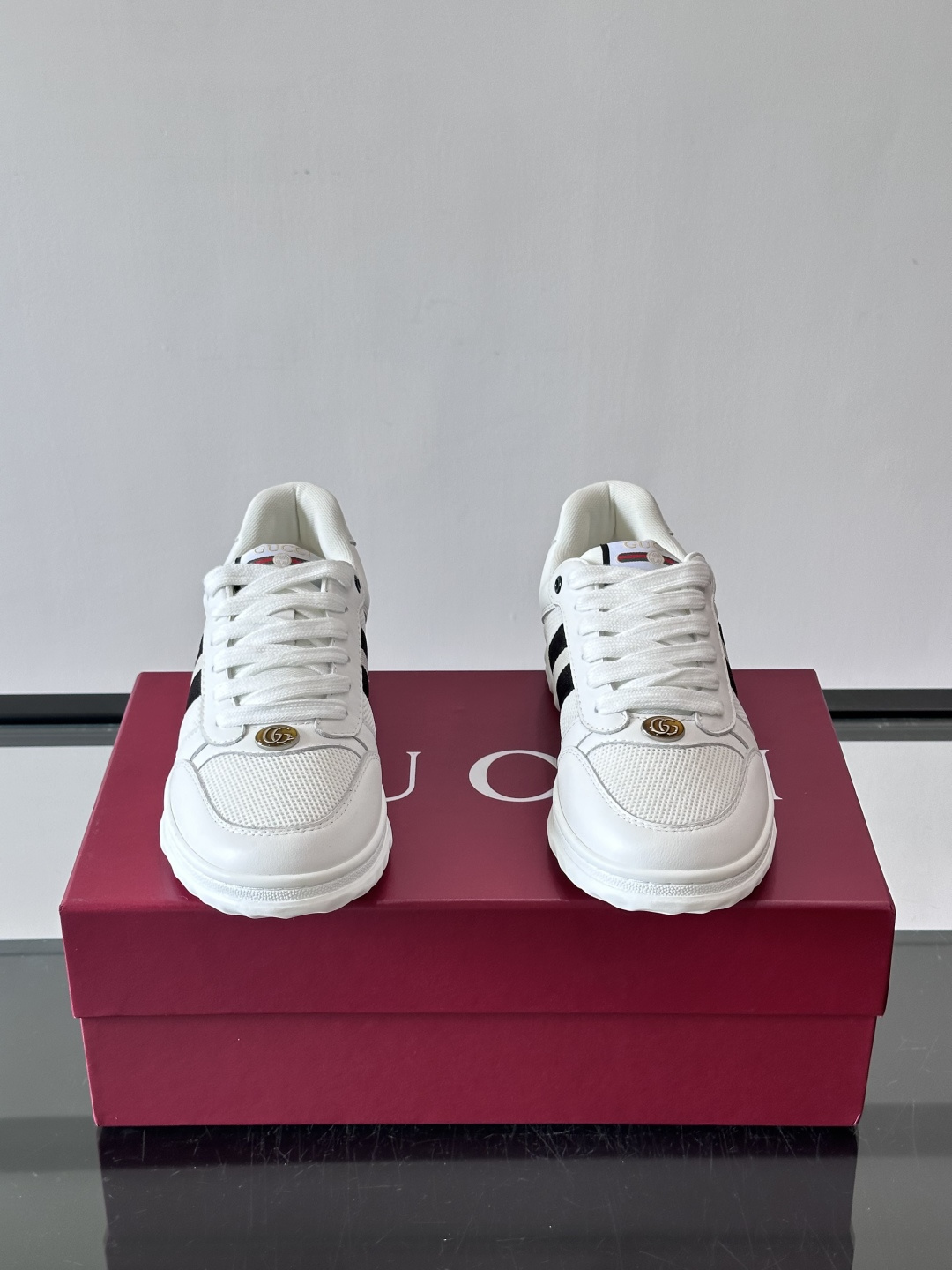 这双也是 ​​Gucci RE-WEB 运动鞋​​，白色皮革鞋身搭配红色织带条纹，金色 GG 金属扣，鞋