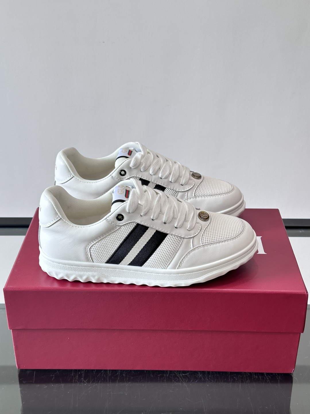 这双也是 ​​Gucci RE-WEB 运动鞋​​，白色皮革鞋身搭配红色织带条纹，金色 GG 金属扣，鞋