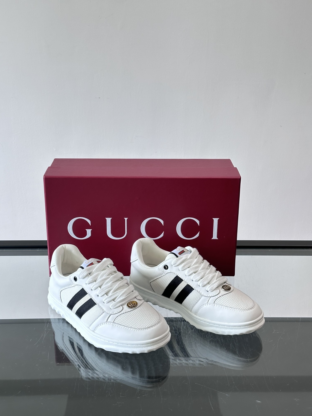这双也是 ​​Gucci RE-WEB 运动鞋​​，白色皮革鞋身搭配红色织带条纹，金色 GG 金属扣，鞋