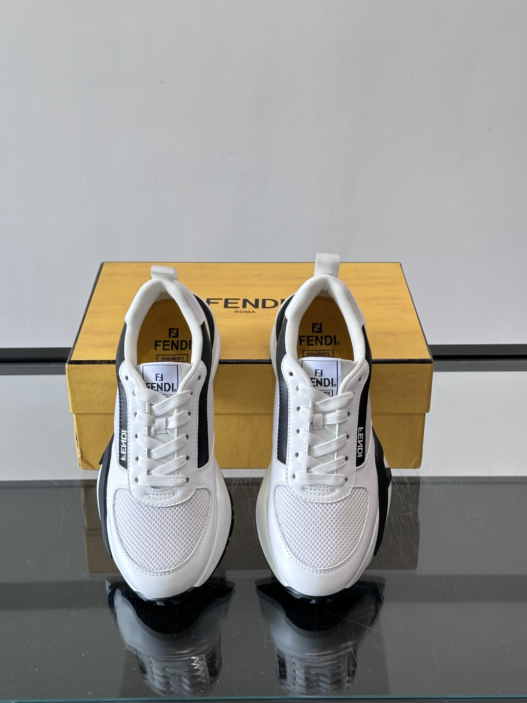 ​​Fendi Flow 运动鞋​​，白色为主色调，网面拼接皮革，黑色 FENDI 品牌条带贯穿侧面，厚