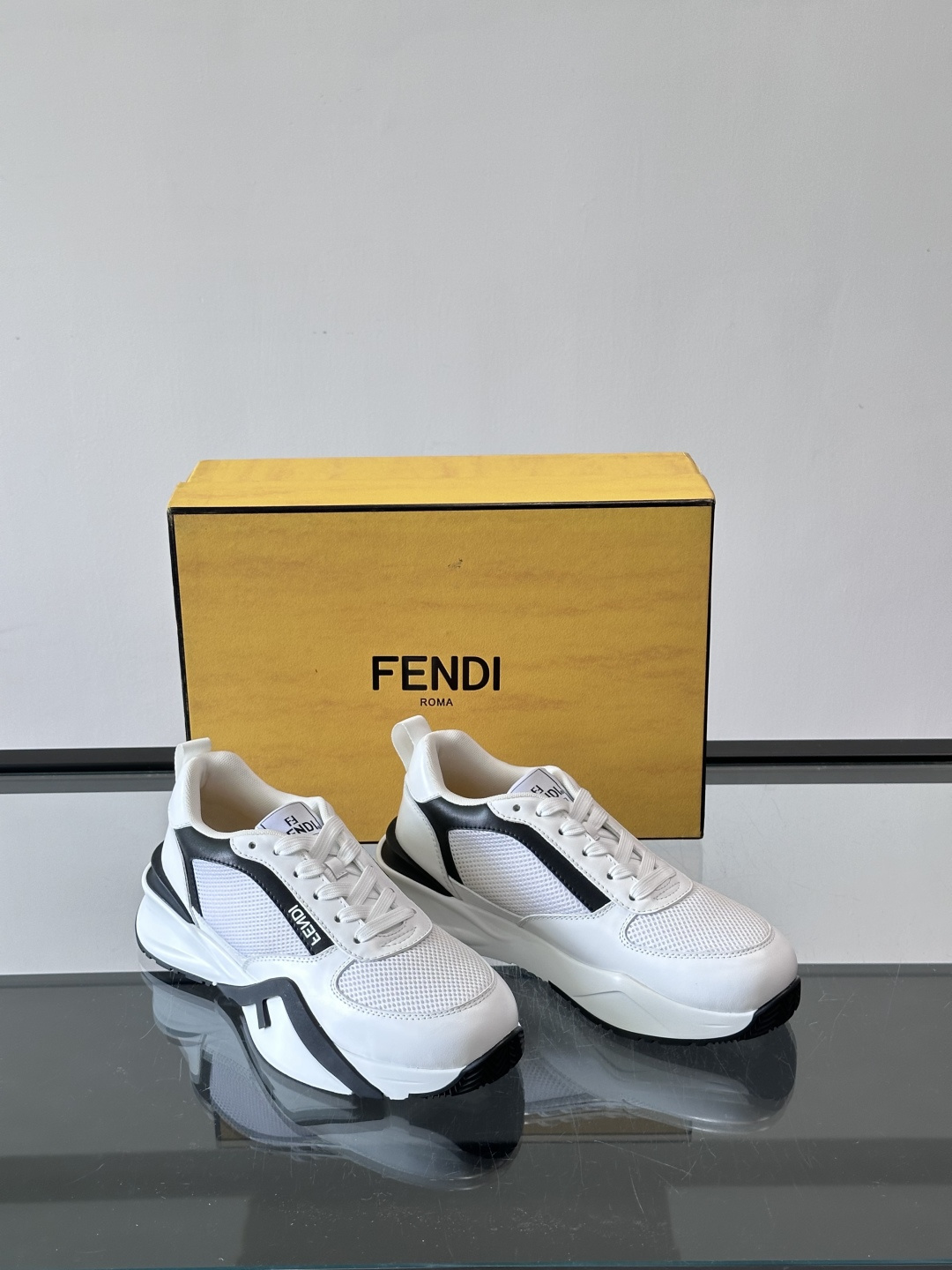 ​​Fendi Flow 运动鞋​​，白色为主色调，网面拼接皮革，黑色 FENDI 品牌条带贯穿侧面，厚