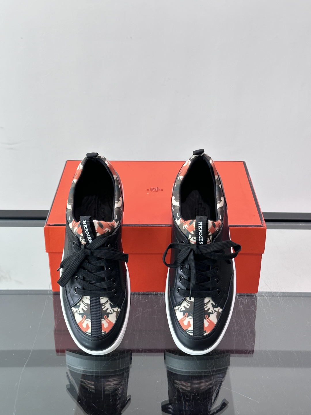 Hermès "Jungle" 迷彩板鞋​​，皮革鞋面搭配迷彩拼接，黑色鞋带和鞋舌"HERMES"字样，白色厚底。这双白