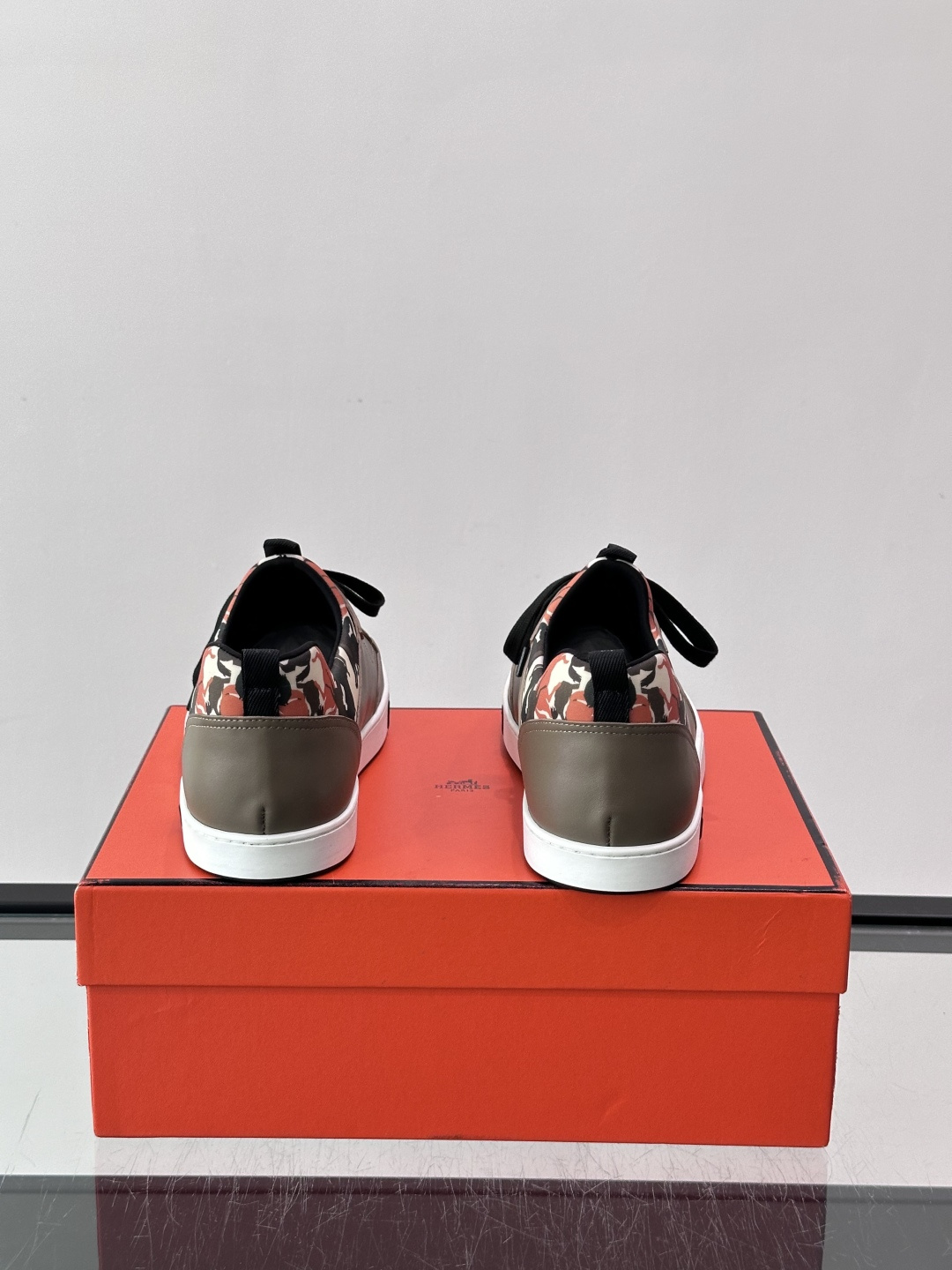 Hermès "Jungle" 迷彩板鞋​​，皮革鞋面搭配迷彩拼接，黑色鞋带和鞋舌"HERMES"字样，白色厚底。这双白