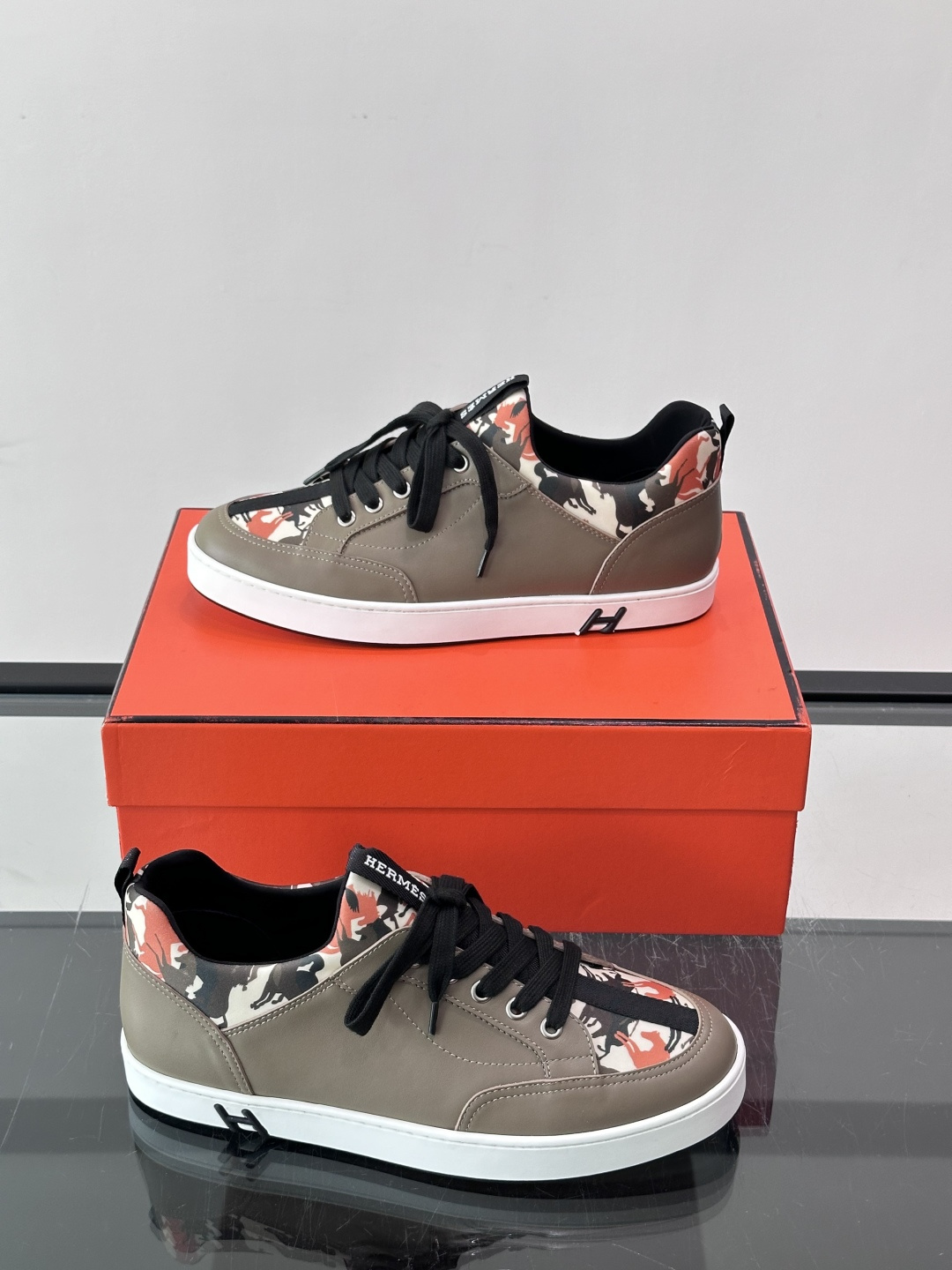 Hermès "Jungle" 迷彩板鞋​​，皮革鞋面搭配迷彩拼接，黑色鞋带和鞋舌"HERMES"字样，白色厚底。这双白