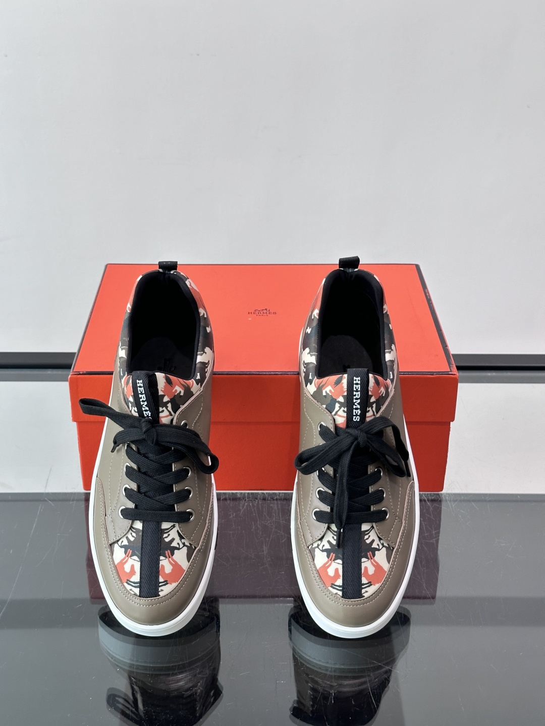 Hermès "Jungle" 迷彩板鞋​​，皮革鞋面搭配迷彩拼接，黑色鞋带和鞋舌"HERMES"字样，白色厚底。这双白