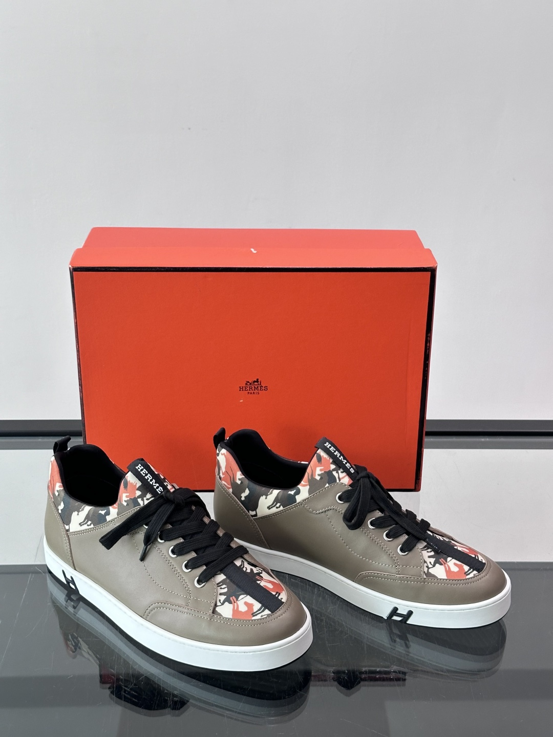 Hermès "Jungle" 迷彩板鞋​​，皮革鞋面搭配迷彩拼接，黑色鞋带和鞋舌"HERMES"字样，白色厚底。这双白