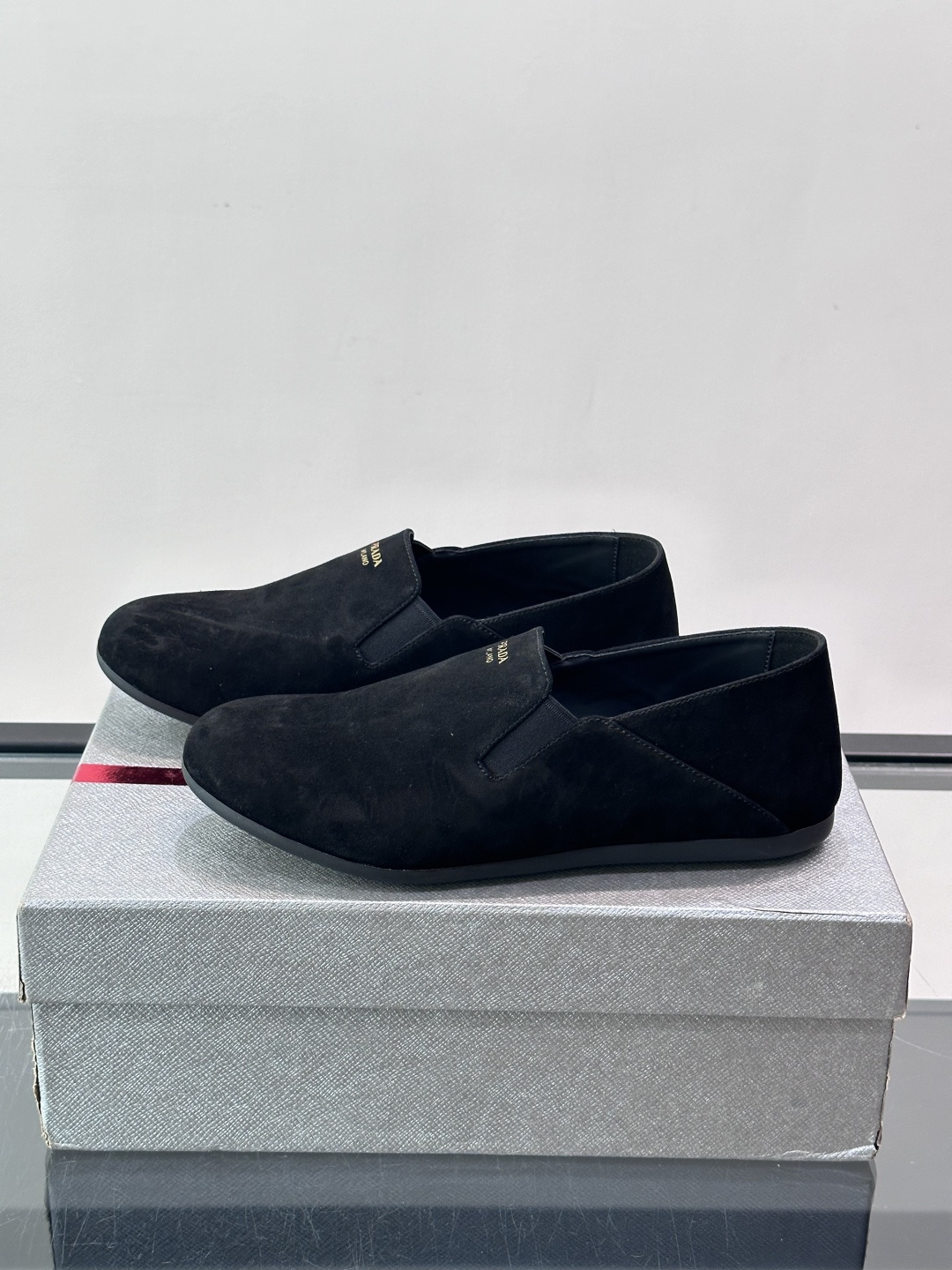 ​​Prada 麂皮一脚蹬乐福鞋​​，翻毛皮鞋面，鞋面顶部有金色"PRADA MILANO"字样烫印，鞋垫上也是 PRA