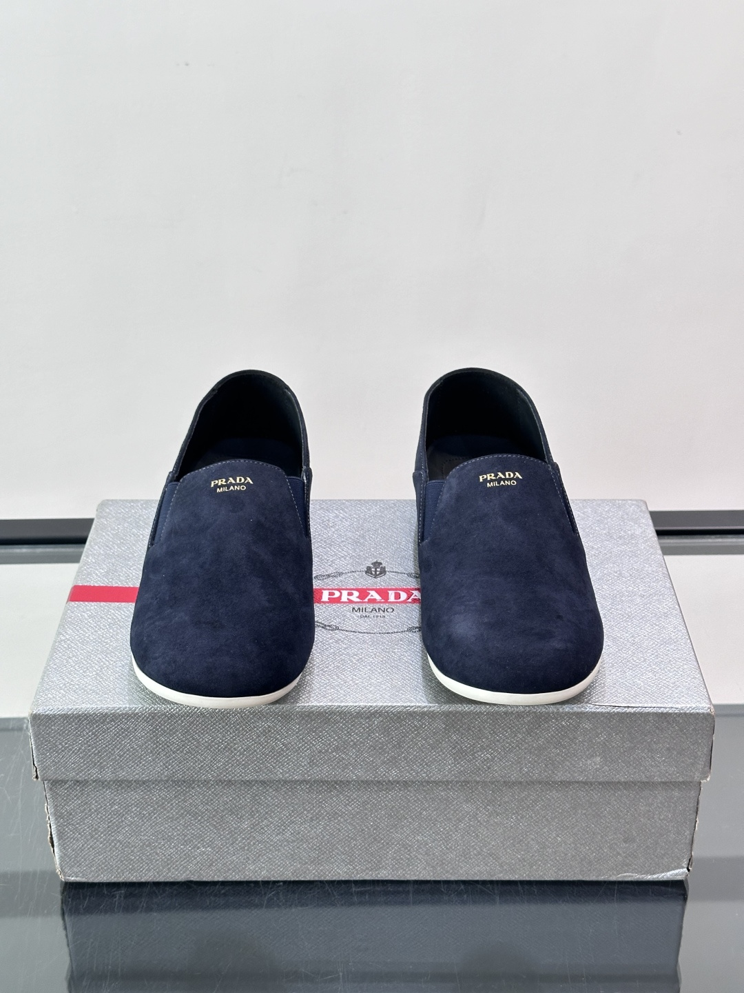​​Prada 麂皮一脚蹬乐福鞋​​，翻毛皮鞋面，鞋面顶部有金色"PRADA MILANO"字样烫印，鞋垫上也是 PRA