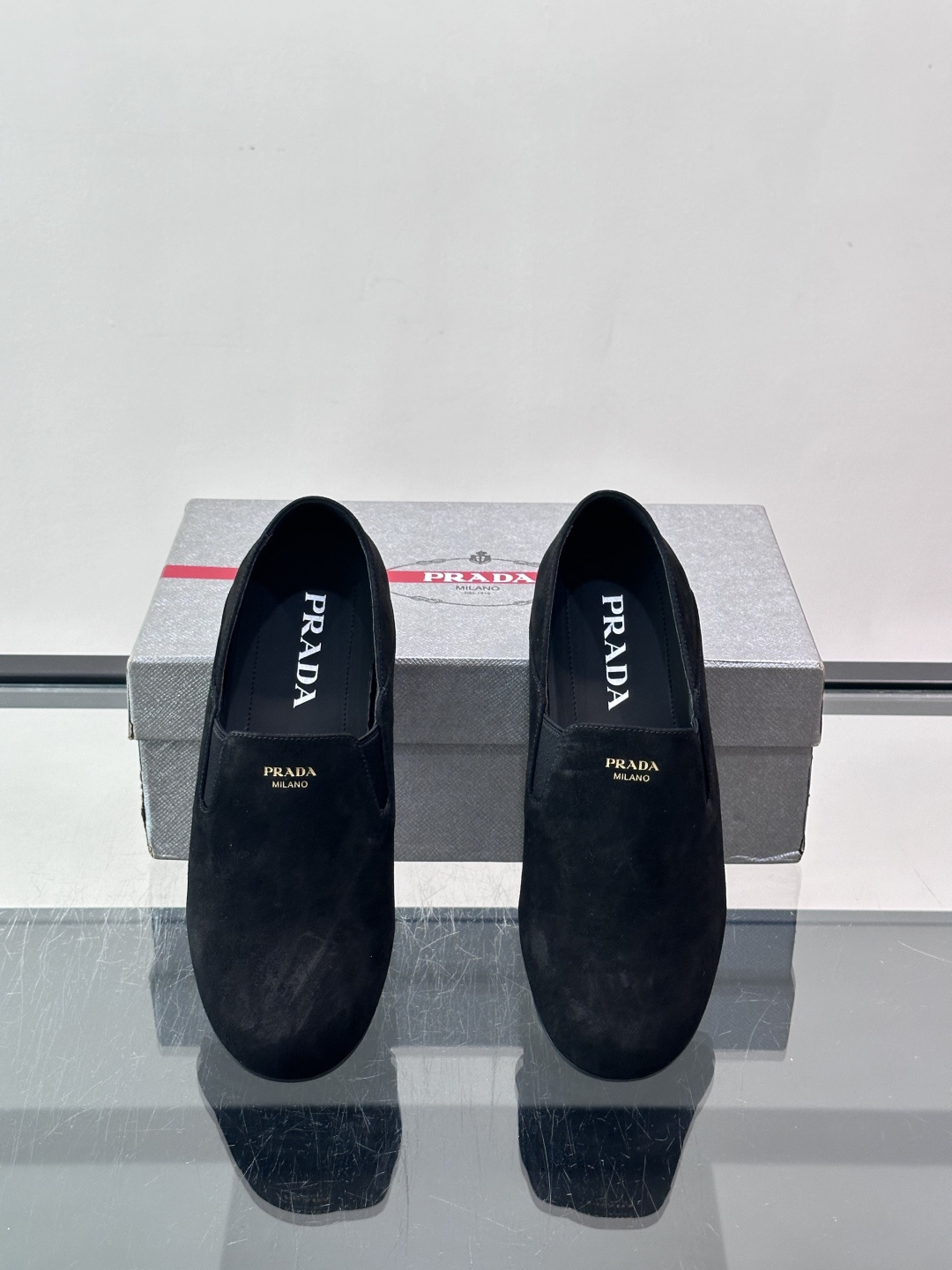 ​​Prada 麂皮一脚蹬乐福鞋​​，翻毛皮鞋面，鞋面顶部有金色"PRADA MILANO"字样烫印，鞋垫上也是 PRA