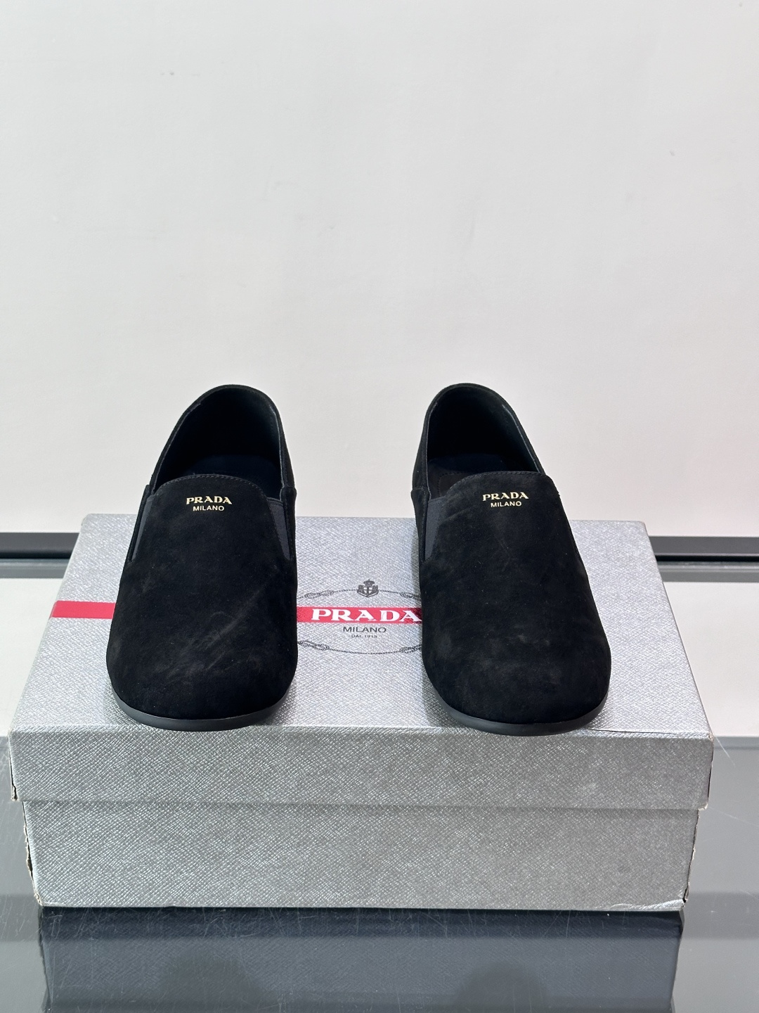 ​​Prada 麂皮一脚蹬乐福鞋​​，翻毛皮鞋面，鞋面顶部有金色"PRADA MILANO"字样烫印，鞋垫上也是 PRA