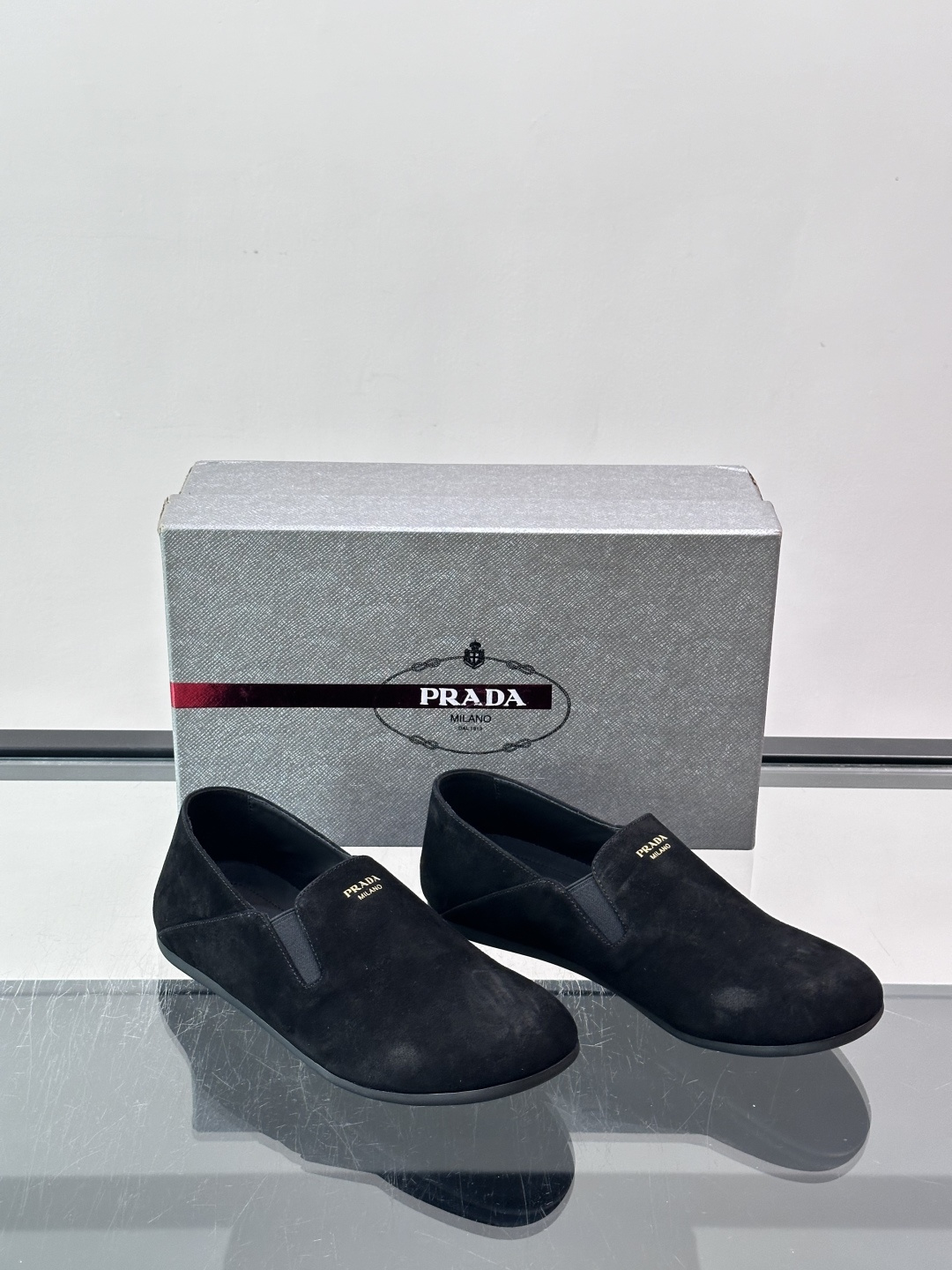​​Prada 麂皮一脚蹬乐福鞋​​，翻毛皮鞋面，鞋面顶部有金色"PRADA MILANO"字样烫印，鞋垫上也是 PRA