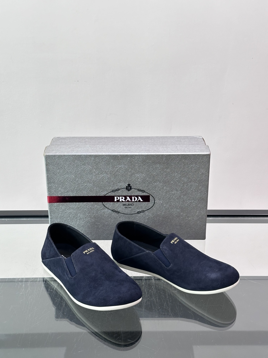 ​​Prada 麂皮一脚蹬乐福鞋​​，翻毛皮鞋面，鞋面顶部有金色"PRADA MILANO"字样烫印，鞋垫上也是 PRA