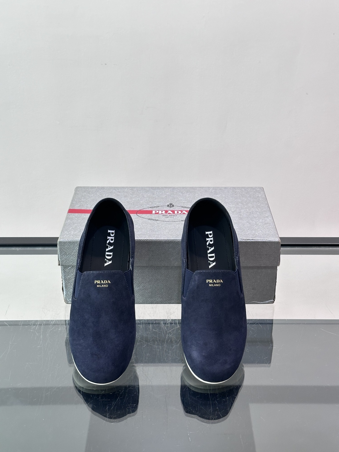 ​​Prada 麂皮一脚蹬乐福鞋​​，翻毛皮鞋面，鞋面顶部有金色"PRADA MILANO"字样烫印，鞋垫上也是 PRA