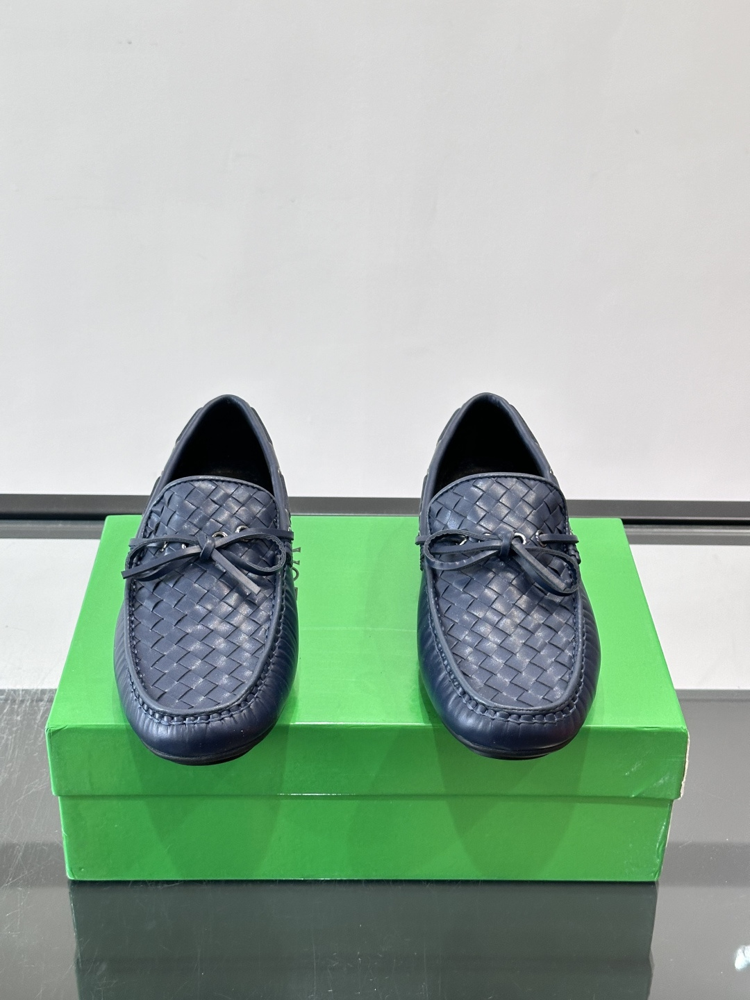 Bottega Veneta 编织豆豆鞋,编织皮革鞋面,皮革系带蝴蝶结,橡胶豆豆颗粒鞋底,包边缝线细节。背景能看到 Bottega Veneta 编织豆豆鞋,编织皮革鞋面,皮革系带蝴蝶结,橡胶豆豆颗粒鞋底,包边缝线细节。背景能看到
