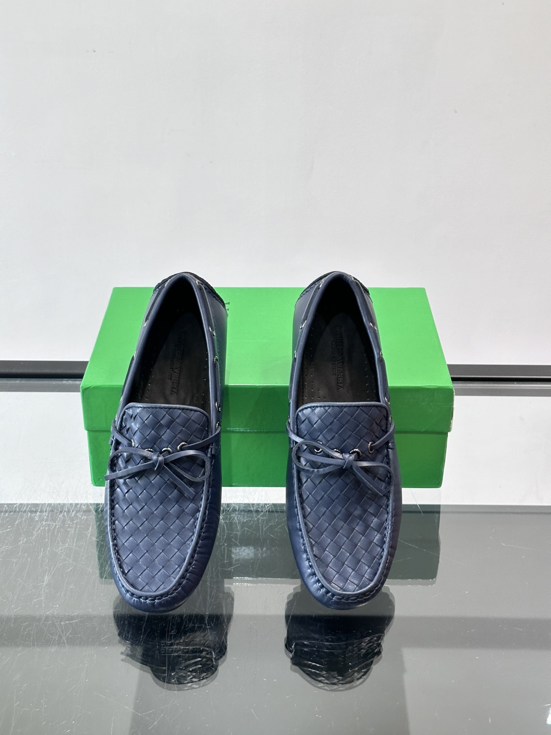 Bottega Veneta 编织豆豆鞋,编织皮革鞋面,皮革系带蝴蝶结,橡胶豆豆颗粒鞋底,包边缝线细节。背景能看到 Bottega Veneta 编织豆豆鞋,编织皮革鞋面,皮革系带蝴蝶结,橡胶豆豆颗粒鞋底,包边缝线细节。背景能看到
