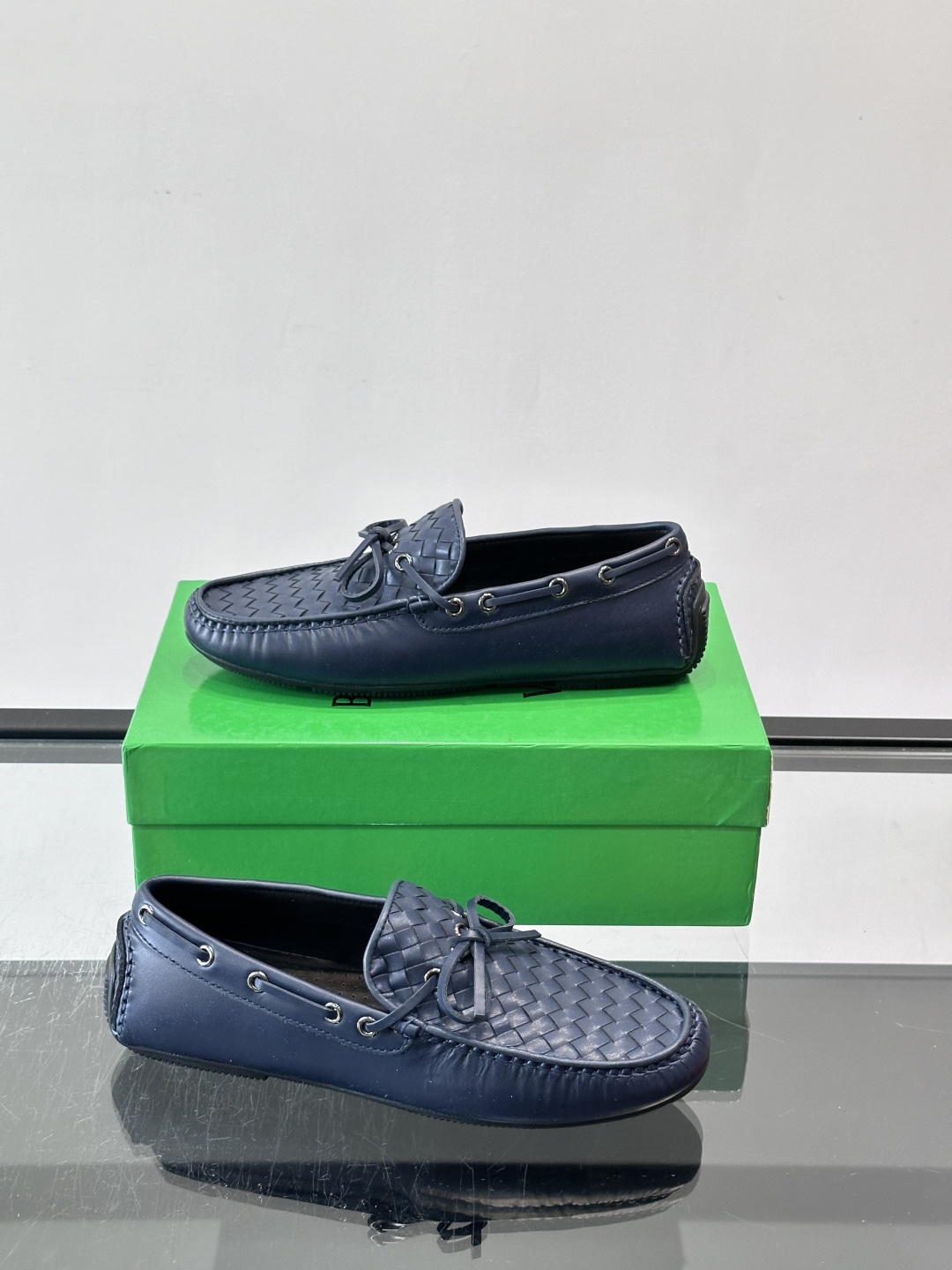 Bottega Veneta 编织豆豆鞋,编织皮革鞋面,皮革系带蝴蝶结,橡胶豆豆颗粒鞋底,包边缝线细节。背景能看到 Bottega Veneta 编织豆豆鞋,编织皮革鞋面,皮革系带蝴蝶结,橡胶豆豆颗粒鞋底,包边缝线细节。背景能看到