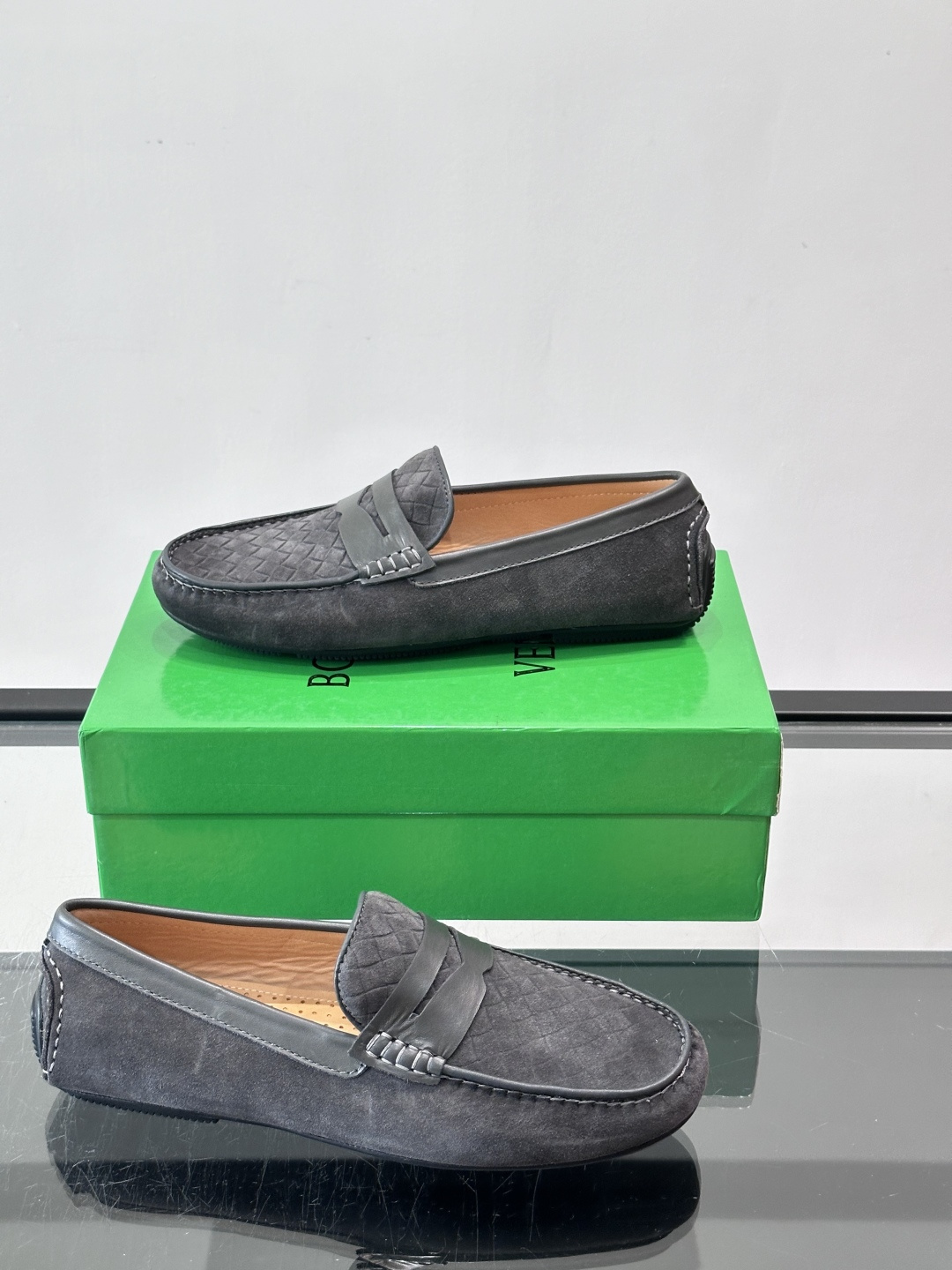Bottega Veneta  编织豆豆鞋​​，编织皮革鞋面，橡胶豆豆颗粒鞋底，包边缝线细节。背景能看到 BV 的经典绿