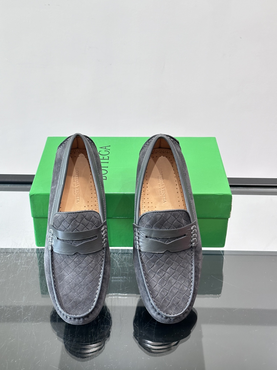 Bottega Veneta  编织豆豆鞋​​，编织皮革鞋面，橡胶豆豆颗粒鞋底，包边缝线细节。背景能看到 BV 的经典绿