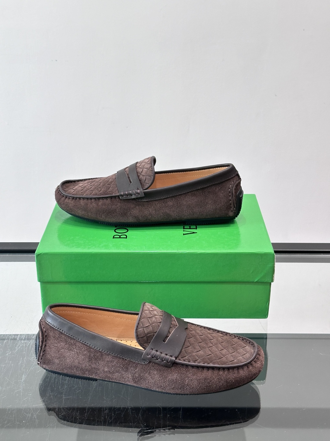 Bottega Veneta  编织豆豆鞋​​，编织皮革鞋面，橡胶豆豆颗粒鞋底，包边缝线细节。背景能看到 BV 的经典绿