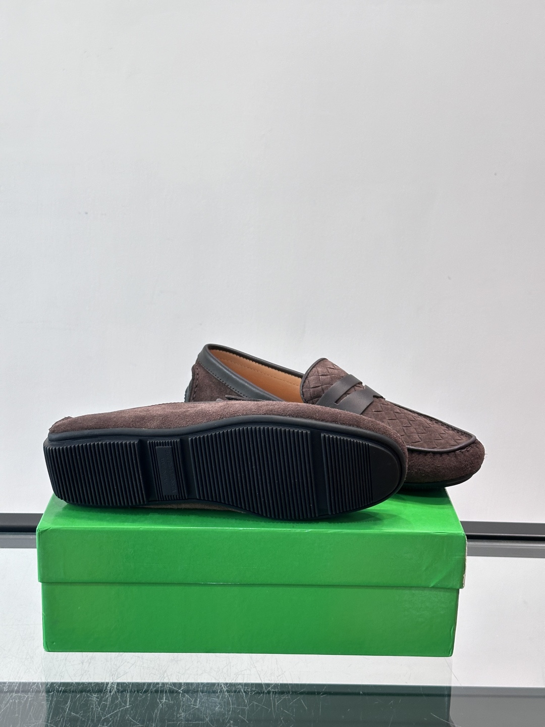 Bottega Veneta  编织豆豆鞋​​，编织皮革鞋面，橡胶豆豆颗粒鞋底，包边缝线细节。背景能看到 BV 的经典绿