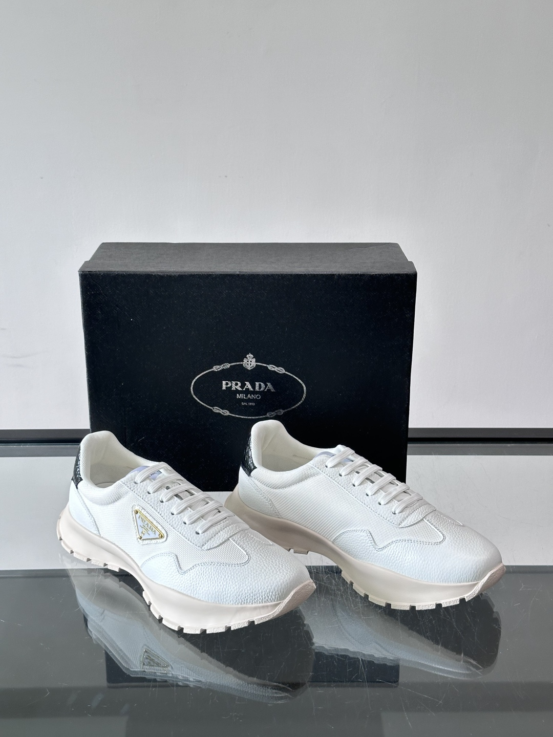 Prada 男士运动鞋,鞋面是荔枝纹皮革 + 网面拼接,鞋侧有金色三角形 Prada 徽标,质感上荔枝纹皮革的颗 Prada 男士运动鞋,鞋面是荔枝纹皮革 + 网面拼接,鞋侧有金色三角形 Prada 徽标,质感上荔枝纹皮革的颗