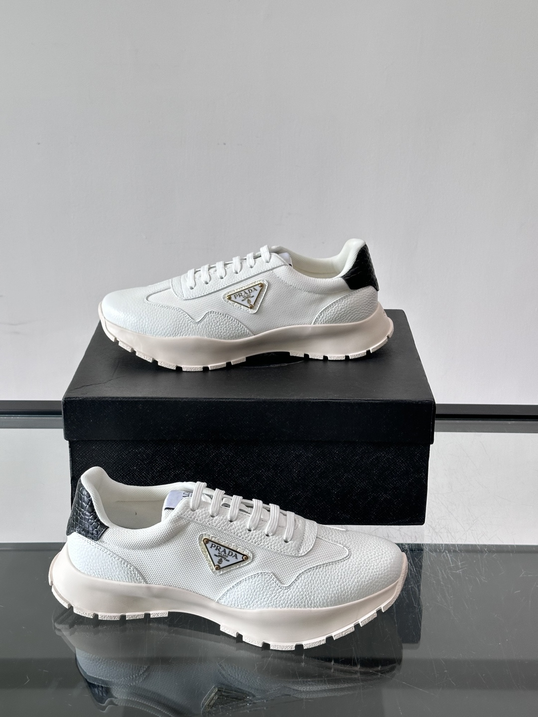Prada 男士运动鞋,鞋面是荔枝纹皮革 + 网面拼接,鞋侧有金色三角形 Prada 徽标,质感上荔枝纹皮革的颗 Prada 男士运动鞋,鞋面是荔枝纹皮革 + 网面拼接,鞋侧有金色三角形 Prada 徽标,质感上荔枝纹皮革的颗