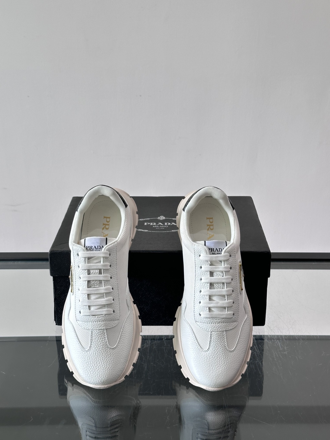 Prada 男士运动鞋,鞋面是荔枝纹皮革 + 网面拼接,鞋侧有金色三角形 Prada 徽标,质感上荔枝纹皮革的颗 Prada 男士运动鞋,鞋面是荔枝纹皮革 + 网面拼接,鞋侧有金色三角形 Prada 徽标,质感上荔枝纹皮革的颗